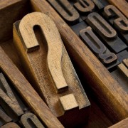 question mark - vintage wooden letterpress type block in old typesetter drawer among other letters stained by ink