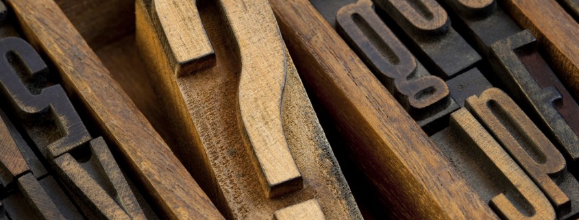 question mark - vintage wooden letterpress type block in old typesetter drawer among other letters stained by ink